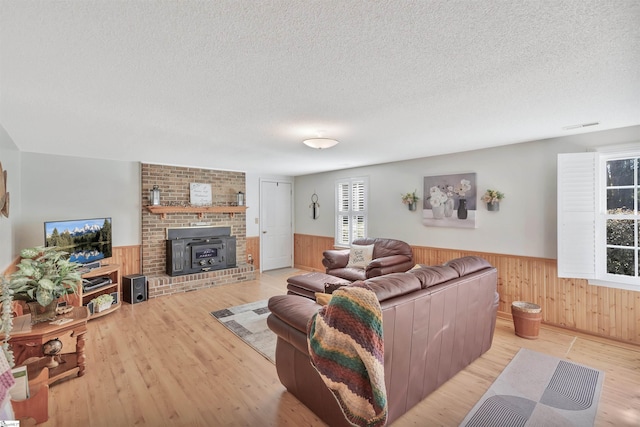 living room featuring a textured ceiling, wooden walls, and light wood-type flooring