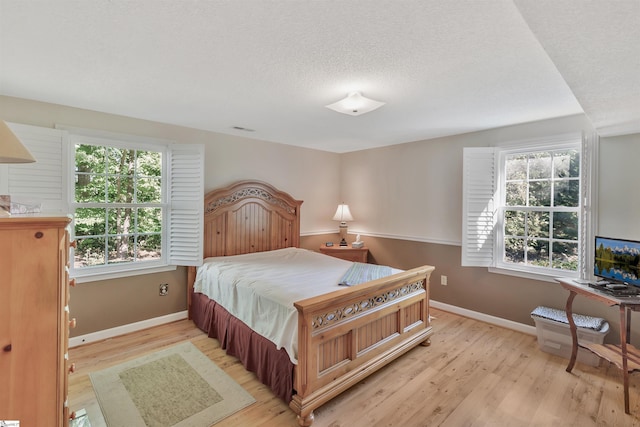 bedroom with a textured ceiling and light wood-type flooring