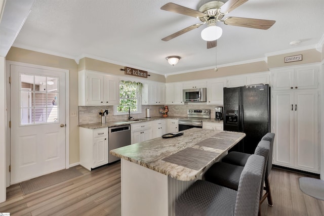 kitchen with light hardwood / wood-style floors, appliances with stainless steel finishes, a center island, and white cabinets