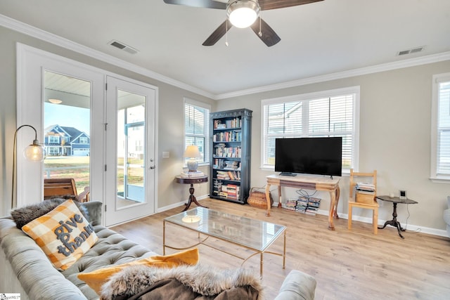 living room featuring light wood-type flooring, ornamental molding, and plenty of natural light