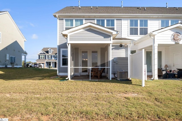 rear view of house featuring cooling unit and a lawn