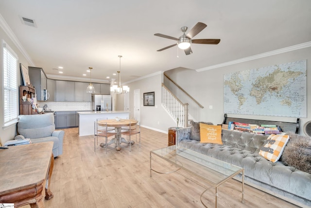 living room featuring crown molding, ceiling fan with notable chandelier, and light hardwood / wood-style floors