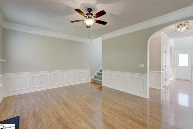 unfurnished room with ceiling fan, ornamental molding, a textured ceiling, and light wood-type flooring