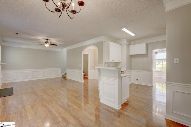 interior space featuring crown molding, light hardwood / wood-style flooring, ceiling fan with notable chandelier, and white cabinets