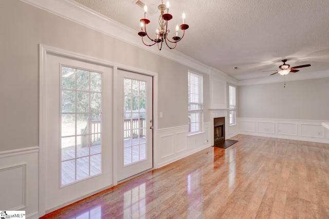 interior space featuring crown molding, a textured ceiling, ceiling fan with notable chandelier, and light wood-type flooring