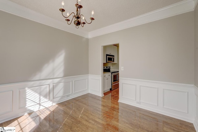 unfurnished room with ornamental molding, a chandelier, a textured ceiling, and light wood-type flooring