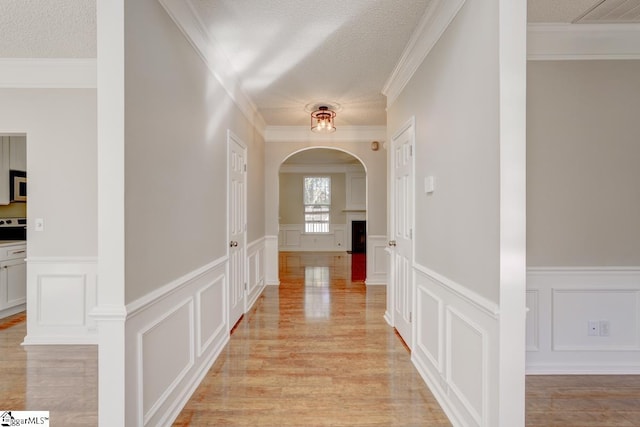 corridor featuring crown molding, light hardwood / wood-style flooring, and a textured ceiling