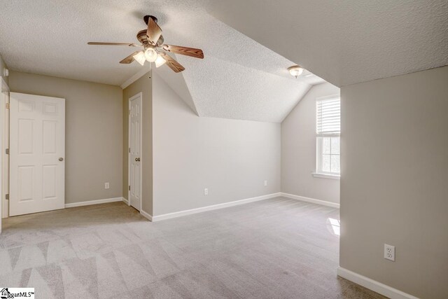 additional living space with light carpet, a textured ceiling, ceiling fan, and vaulted ceiling