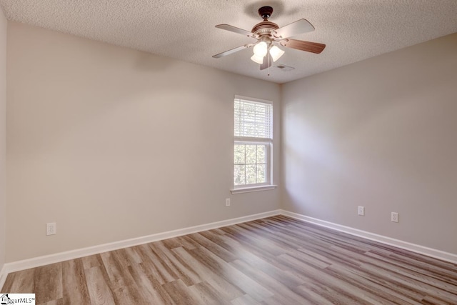 empty room featuring a textured ceiling, light wood-type flooring, and ceiling fan