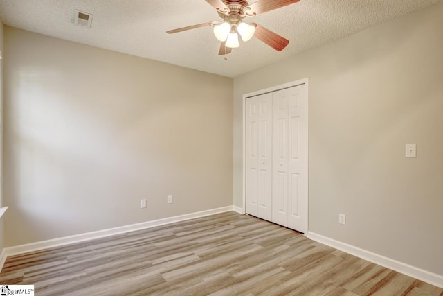 unfurnished bedroom featuring light hardwood / wood-style flooring, a textured ceiling, and ceiling fan