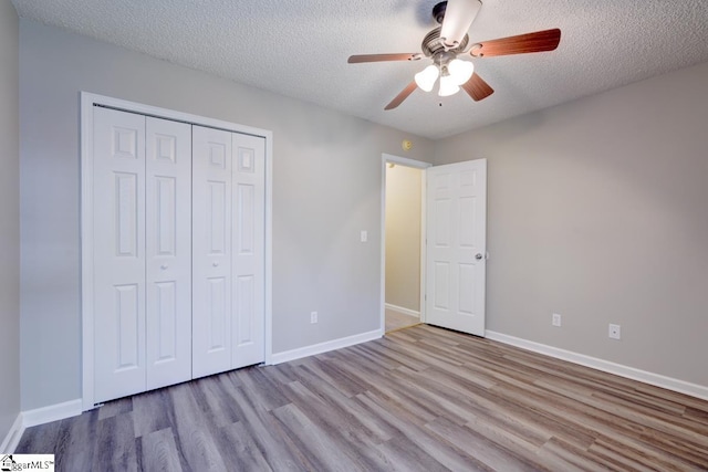 unfurnished bedroom with light hardwood / wood-style flooring, a textured ceiling, a closet, and ceiling fan