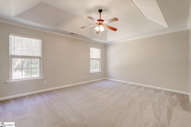 unfurnished room with ceiling fan, a raised ceiling, ornamental molding, and light colored carpet