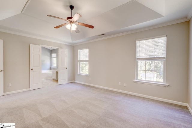 carpeted empty room with ornamental molding, ceiling fan, and a raised ceiling