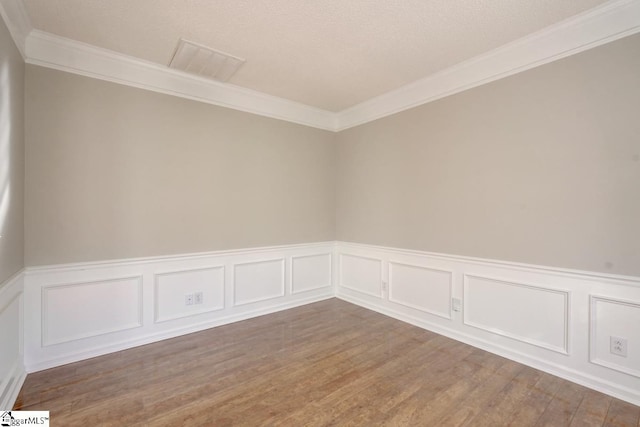 spare room with crown molding, a textured ceiling, and hardwood / wood-style floors