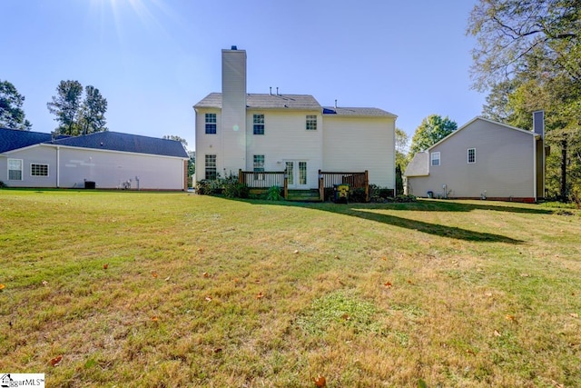 rear view of house featuring a wooden deck and a lawn