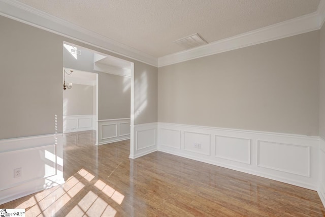 unfurnished room with crown molding, a textured ceiling, and light wood-type flooring