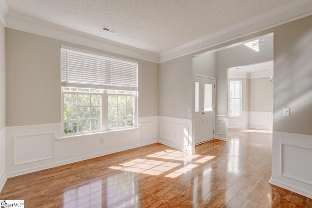 spare room featuring ornamental molding, a textured ceiling, and light wood-type flooring