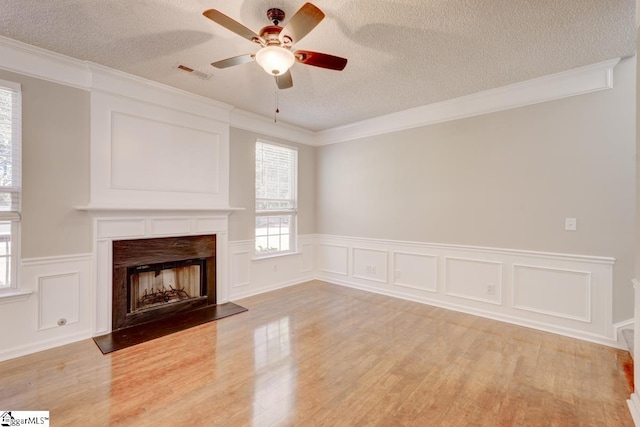 unfurnished living room with a textured ceiling, light hardwood / wood-style flooring, and ornamental molding