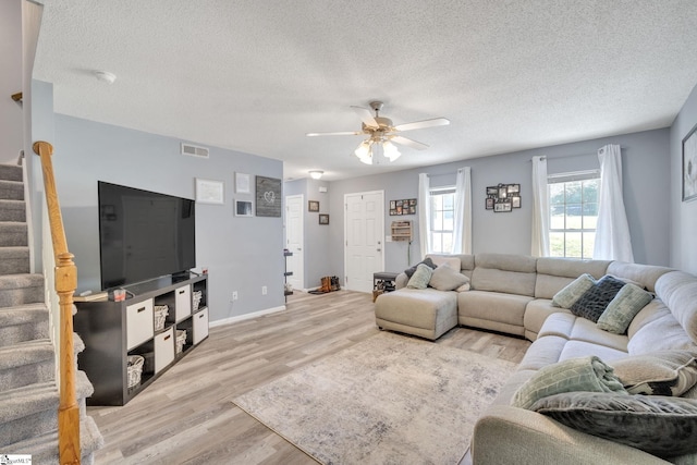 living room featuring ceiling fan, a textured ceiling, and light wood-type flooring