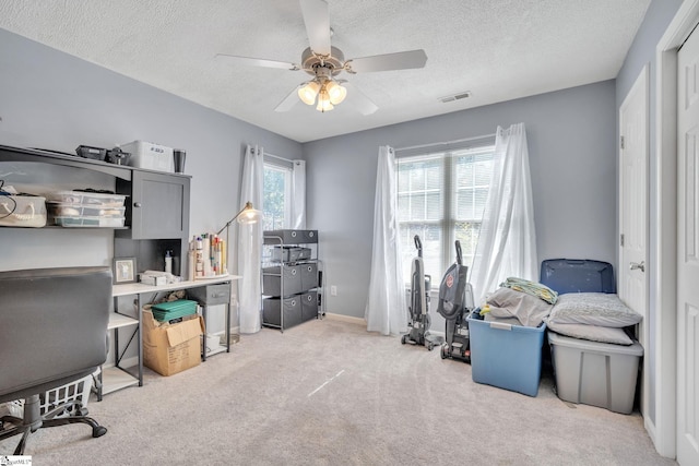 office space featuring light carpet, a textured ceiling, and ceiling fan