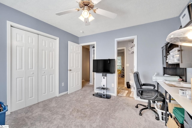 office area with a textured ceiling, light colored carpet, and ceiling fan