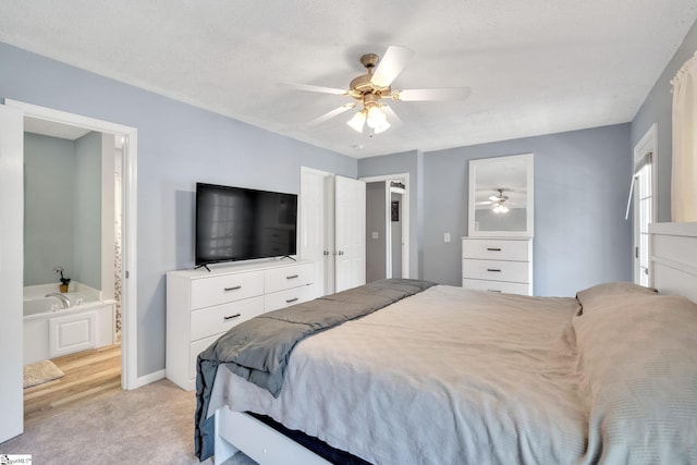 bedroom featuring connected bathroom, a textured ceiling, light colored carpet, and ceiling fan