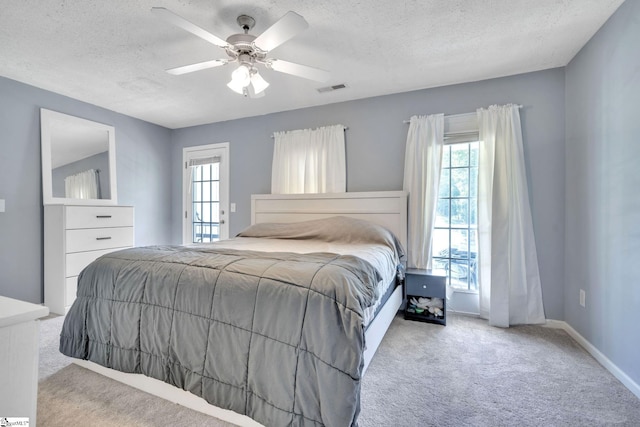 carpeted bedroom featuring a textured ceiling, multiple windows, and ceiling fan