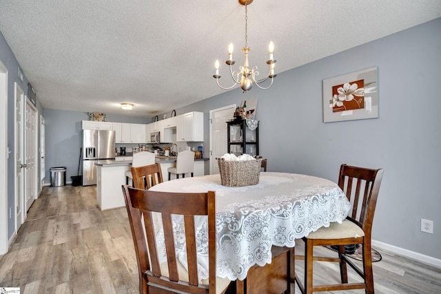 dining area with a notable chandelier, a textured ceiling, and light wood-type flooring