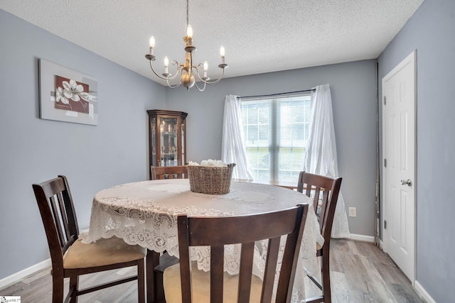 dining space with hardwood / wood-style floors, a notable chandelier, and a textured ceiling