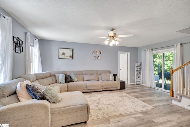 living room featuring light hardwood / wood-style flooring, a textured ceiling, and ceiling fan