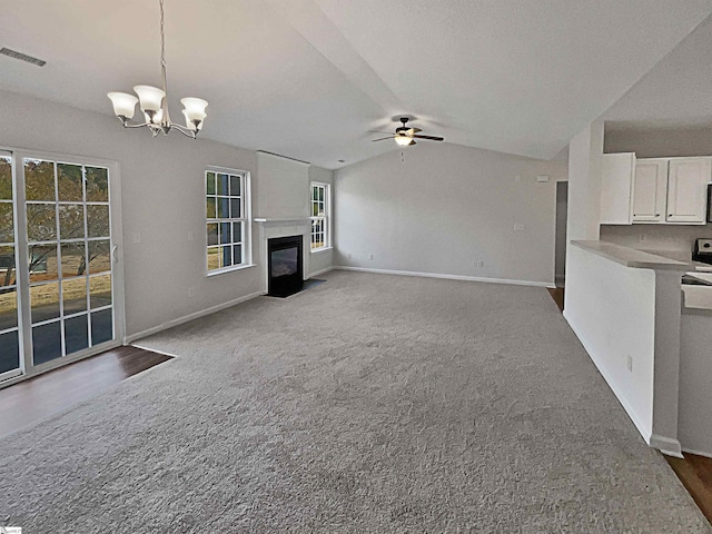 unfurnished living room with vaulted ceiling, ceiling fan with notable chandelier, and carpet floors