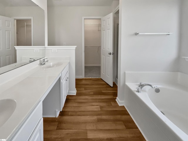 bathroom with vanity, hardwood / wood-style floors, and a relaxing tiled tub