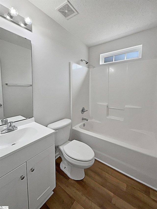 full bathroom featuring a textured ceiling, hardwood / wood-style flooring, toilet, vanity, and shower / bath combination