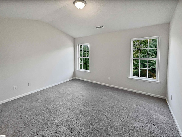 carpeted spare room featuring a textured ceiling and vaulted ceiling