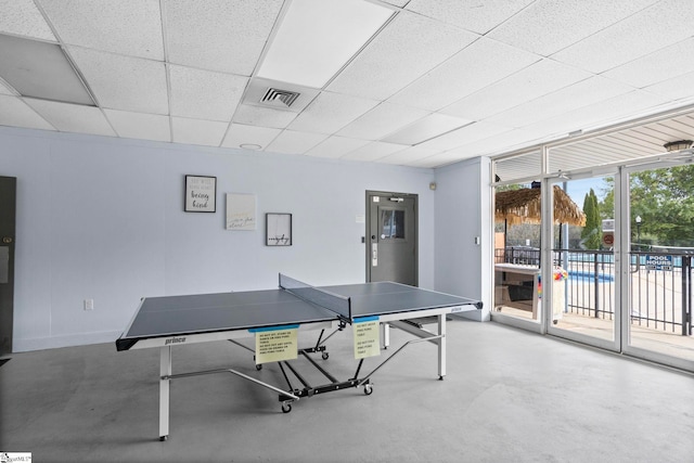 recreation room with a drop ceiling and concrete floors