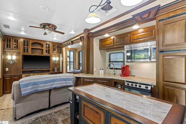 kitchen featuring ceiling fan, sink, ornamental molding, and stainless steel appliances