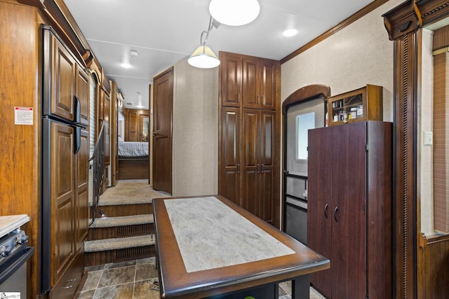 kitchen featuring fridge, dark tile patterned flooring, stainless steel range oven, and crown molding