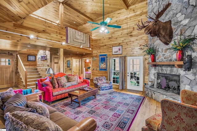 living room with high vaulted ceiling, wooden ceiling, light wood-type flooring, wood walls, and a fireplace