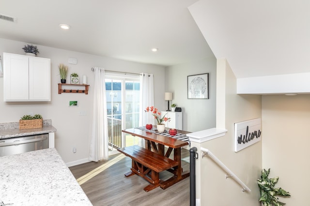 interior space with light stone countertops, light hardwood / wood-style flooring, stainless steel dishwasher, and white cabinets