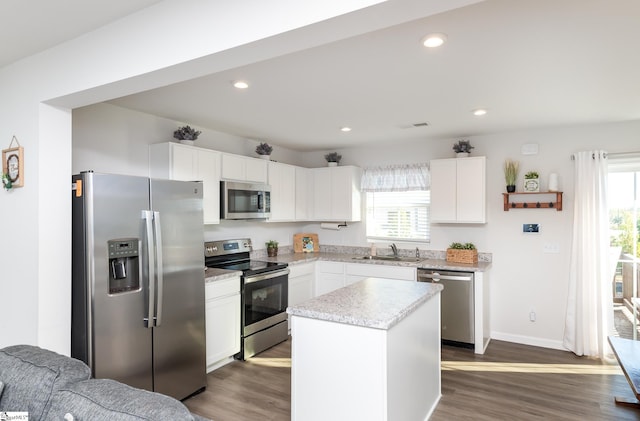 kitchen with appliances with stainless steel finishes, dark hardwood / wood-style flooring, a center island, and a wealth of natural light