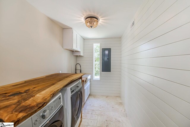 kitchen with white cabinets, separate washer and dryer, wooden walls, wooden counters, and electric panel