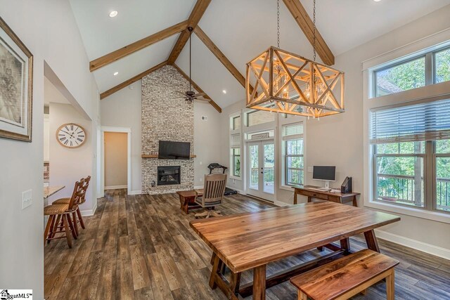 dining space with dark wood-type flooring, high vaulted ceiling, french doors, and a stone fireplace