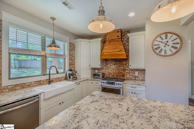 kitchen featuring premium range hood, white cabinets, stainless steel appliances, and sink