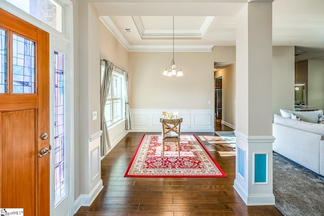 entrance foyer featuring dark wood-type flooring, a tray ceiling, crown molding, and a notable chandelier