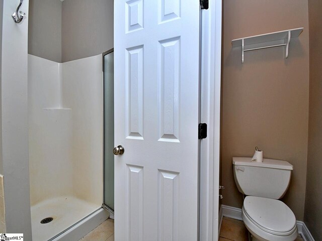 bathroom featuring toilet, a shower, and tile patterned flooring