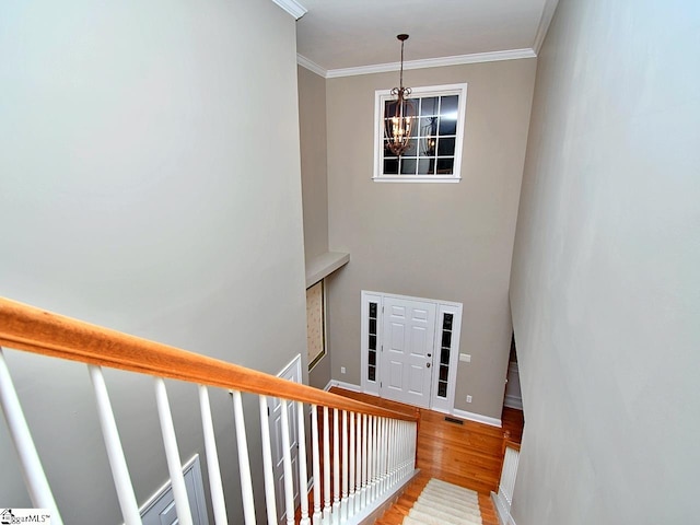 staircase featuring ornamental molding, hardwood / wood-style floors, and a chandelier