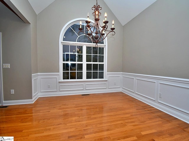 unfurnished dining area featuring light hardwood / wood-style floors, vaulted ceiling, and an inviting chandelier