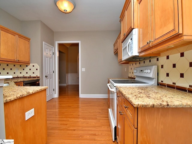 kitchen with white appliances, tasteful backsplash, light stone countertops, and light wood-type flooring