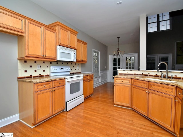 kitchen with backsplash, sink, light wood-type flooring, a chandelier, and white appliances