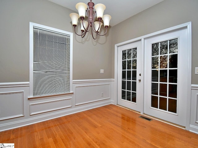 unfurnished dining area with an inviting chandelier and hardwood / wood-style floors